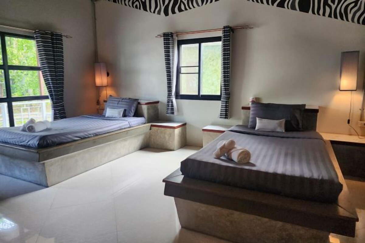 A bedroom with two beds, a window, and a zebra-patterned ceiling.