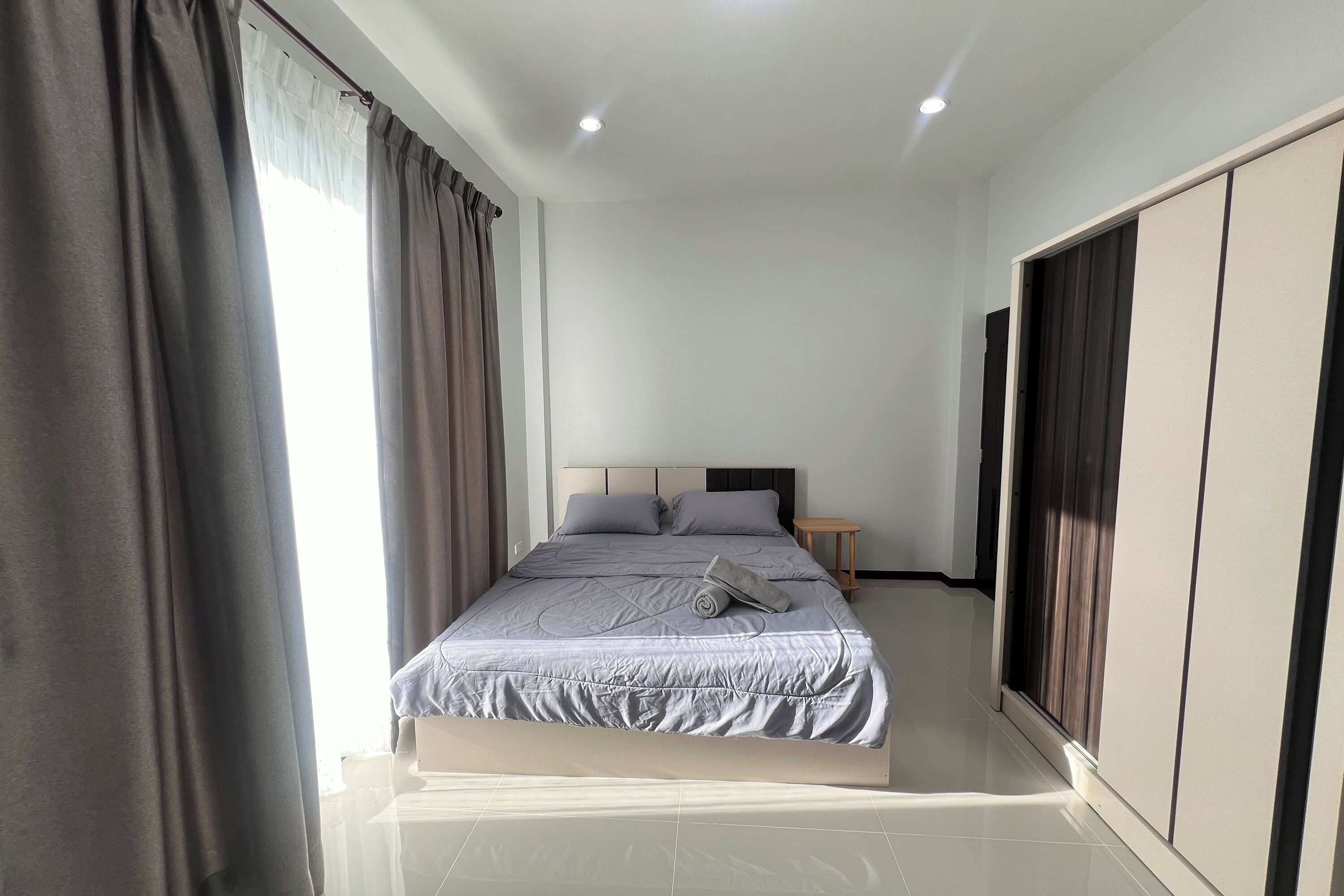 Une chambre à coucher moderne avec un grand lit, une table de chevet et une armoire.