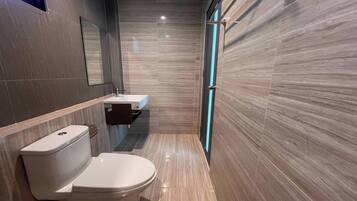 Un baño moderno con inodoro, lavamanos y espejo.