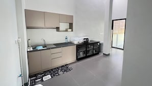 A modern kitchen with a countertop, sink, cabinets, and a window. - Poome House (Hat Yai)