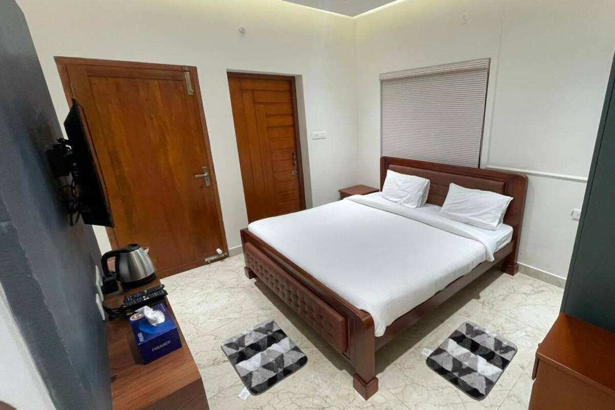 Quarto com cama de madeira, mesa de cabeceira, chaleira e uma caixa com a inscrição 'Premier'.