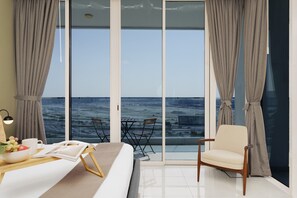 Une chambre d’hôtel moderne dotée d’une grande porte-fenêtre coulissante donnant sur un balcon avec vue sur la ville.