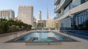 Ein Pool auf dem Dach mit Stadtansicht im Hintergrund, umgeben von modernen Gebäuden und Grünflächen.