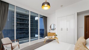 Ein modernes Hotelzimmer mit großem Fenster, Schreibtisch mit Spiegel, Stuhl und Bett.