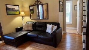 A living room with a sectional sofa, a lamp, and framed pictures on the walls.