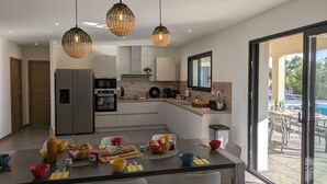 A modern kitchen with a central island, built-in appliances, and pendant lighting. - New Villa Floria**** with Private Heated Pool in South Ardèche (Joyeuse)