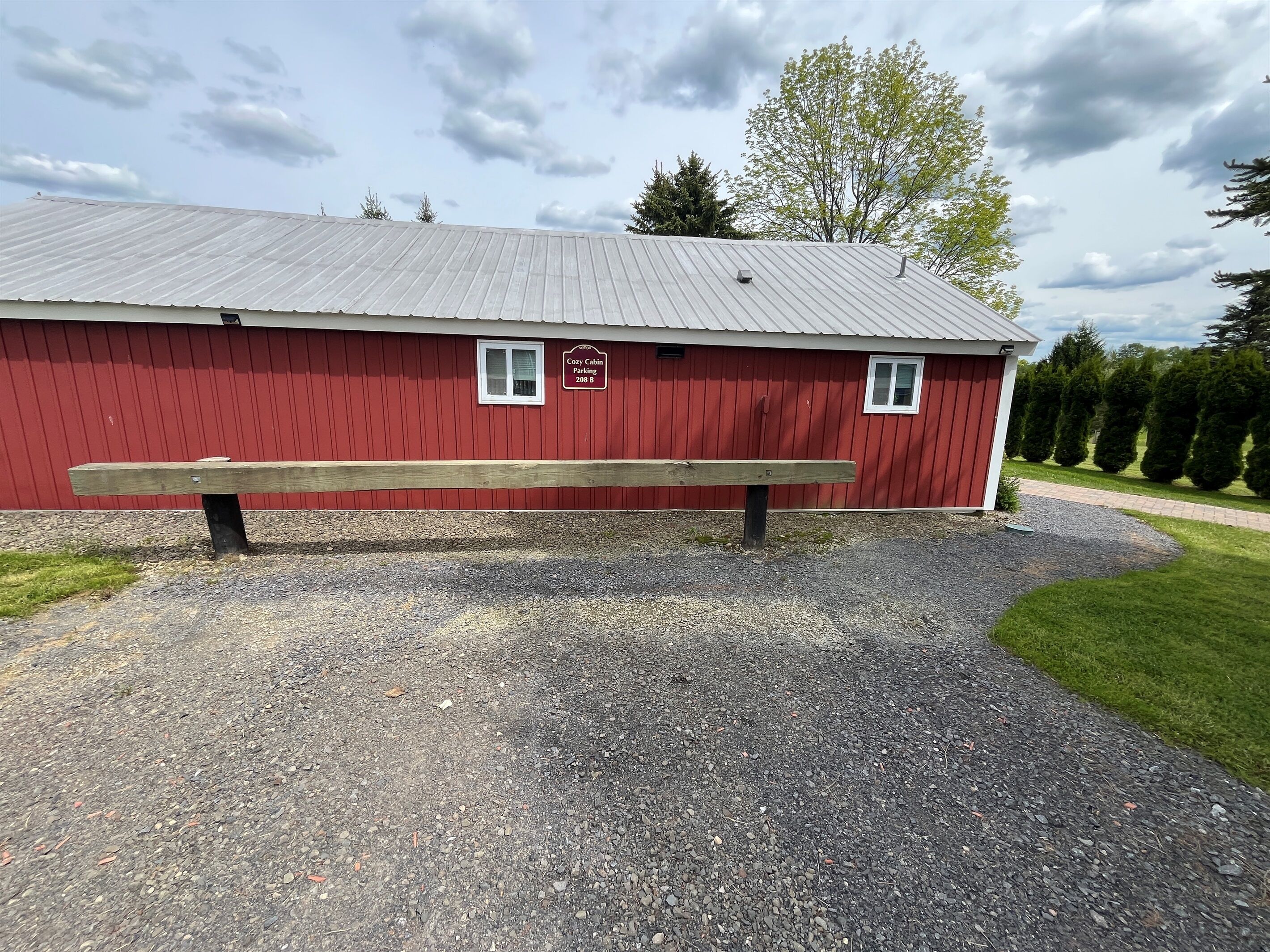 A red building with a gravel driveway and a wooden bench in front.