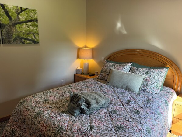 Una cama bien hecha con ropa de cama floral, un cabecero de madera y una lámpara de noche.