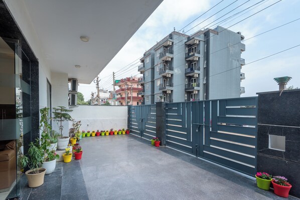 A modern building with a balcony, potted plants, and a gated entrance.