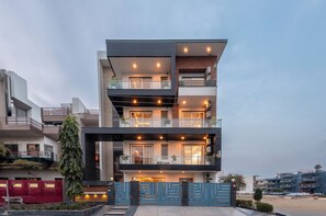 A modern multi-story residential building with balconies, large windows, and a gated entrance.