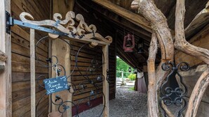 A rustic wooden entrance with a chalkboard sign, metal hooks for coats, and a lantern hanging from the ceiling. - Gaia" Hobbit House (Vittel)