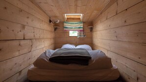 A small, narrow room with wooden walls and a single bed with white bedding. - Gaia" Hobbit House (Vittel)
