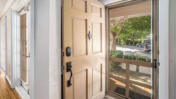 A beige door with a keypad lock and a glass door leading to a porch.
