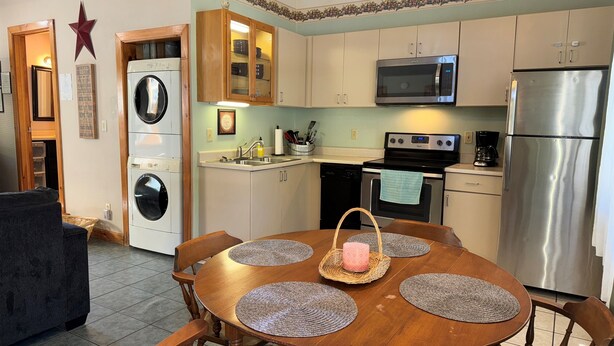 Una cocina funcional con microondas, horno y refrigerador. Hay una mesa de comedor con individuales y una cesta.