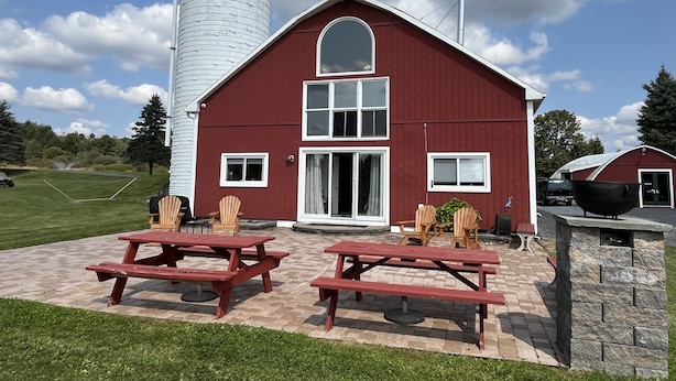 A red barn with a silo, picnic tables, and a stone wall.