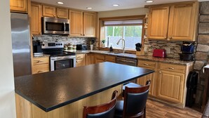A kitchen with wooden cabinets, stainless steel appliances, a granite countertop, and a window with a view.