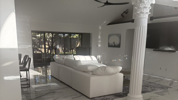 A spacious living area with a white sofa, a marble floor, and a large column. - Mini Resort , 3 BR newly renovated, Gym , pool , spa , pickleball,basketball (Naples)