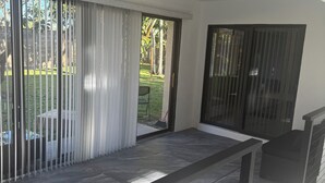 A spacious balcony with a ceiling fan, large sliding glass doors, and a view of a garden. - Mini Resort , 3 BR newly renovated, Gym , pool , spa , pickleball,basketball (Naples)