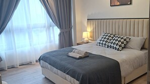 A modern bedroom with a large bed, a headboard, a bedside table with a lamp, and a wall-mounted artwork. - AGILE Service Residence by Sha (Kuala Lumpur)