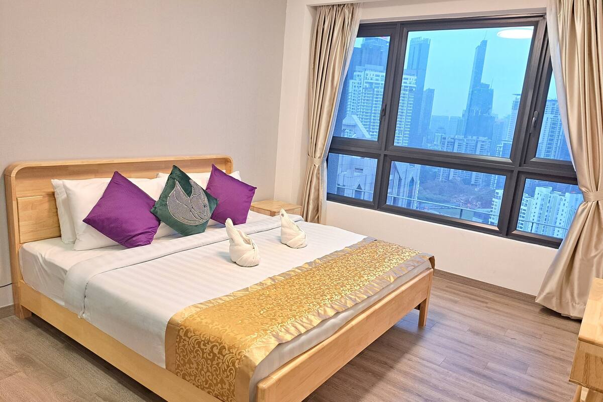 A neatly made bed with a patterned bedspread, a wooden headboard, and decorative pillows.