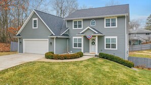 A two-story house with a garage, a front porch, and a small front yard.