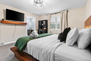 Une chambre à coucher avec un lit, une télévision, une armoire et une fenêtre avec des rideaux.