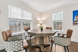 Un coin repas avec une table ronde, des chaises en osier et un lampadaire.