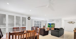 Un salon moderne comprenant un coin repas, un téléviseur et un ventilateur de plafond.