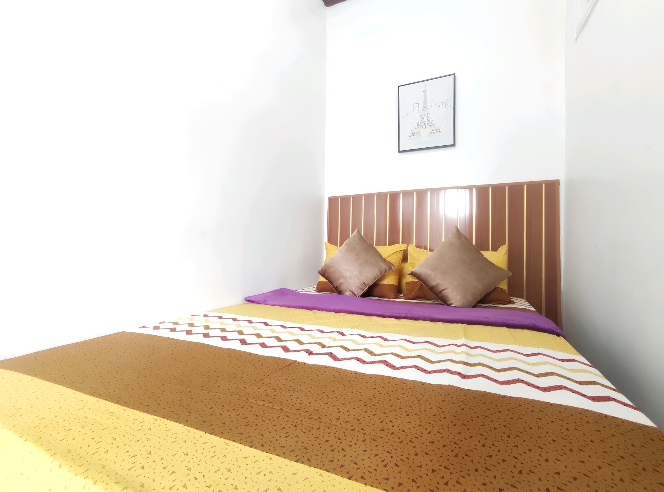 A bed with a patterned bedspread, pillows, and a headboard.