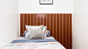Un dormitorio con cabecera de madera, una cama con ropa de cama estampada y un cuadro en la pared.