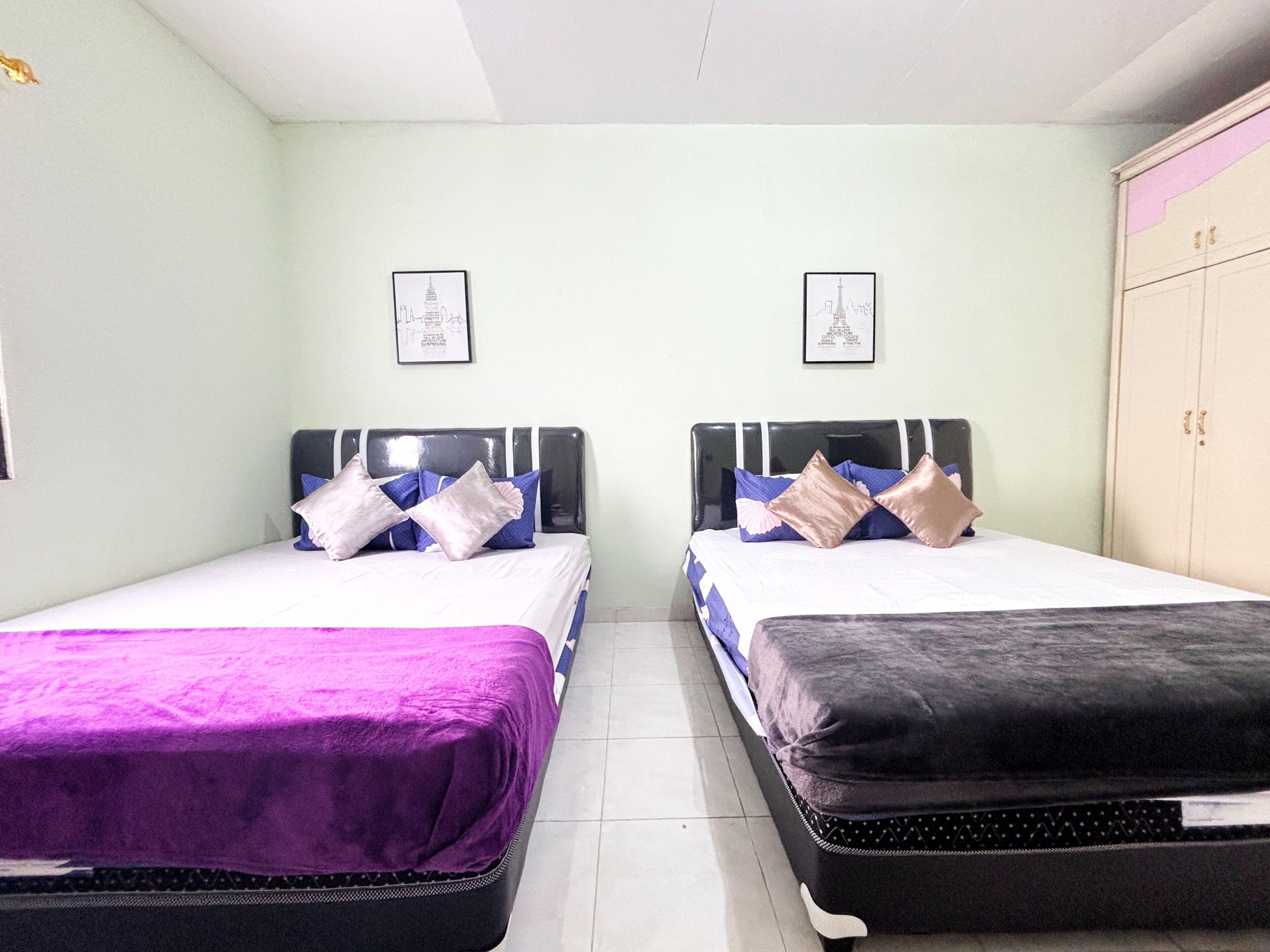 A room with two beds, each with a headboard, and a wardrobe.