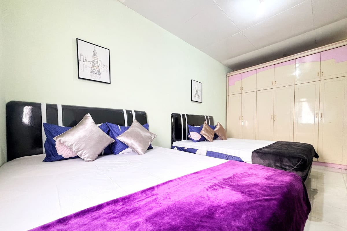 Quarto com duas camas, cada uma com cabeceira, e um guarda-roupa com várias portas.
