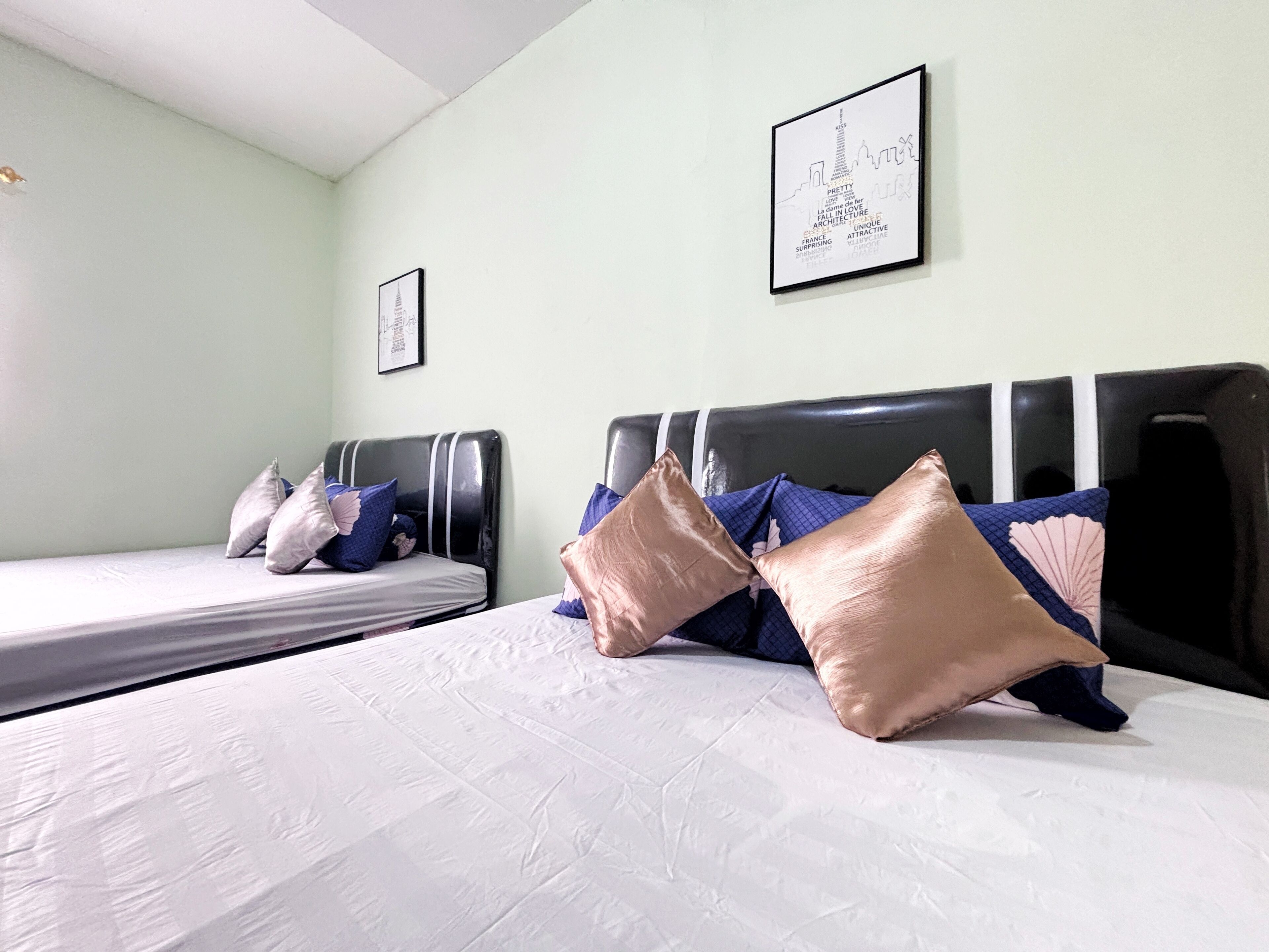 Habitación de hotel con dos camas, cada una con cabecera, y un cuadro enmarcado en la pared.