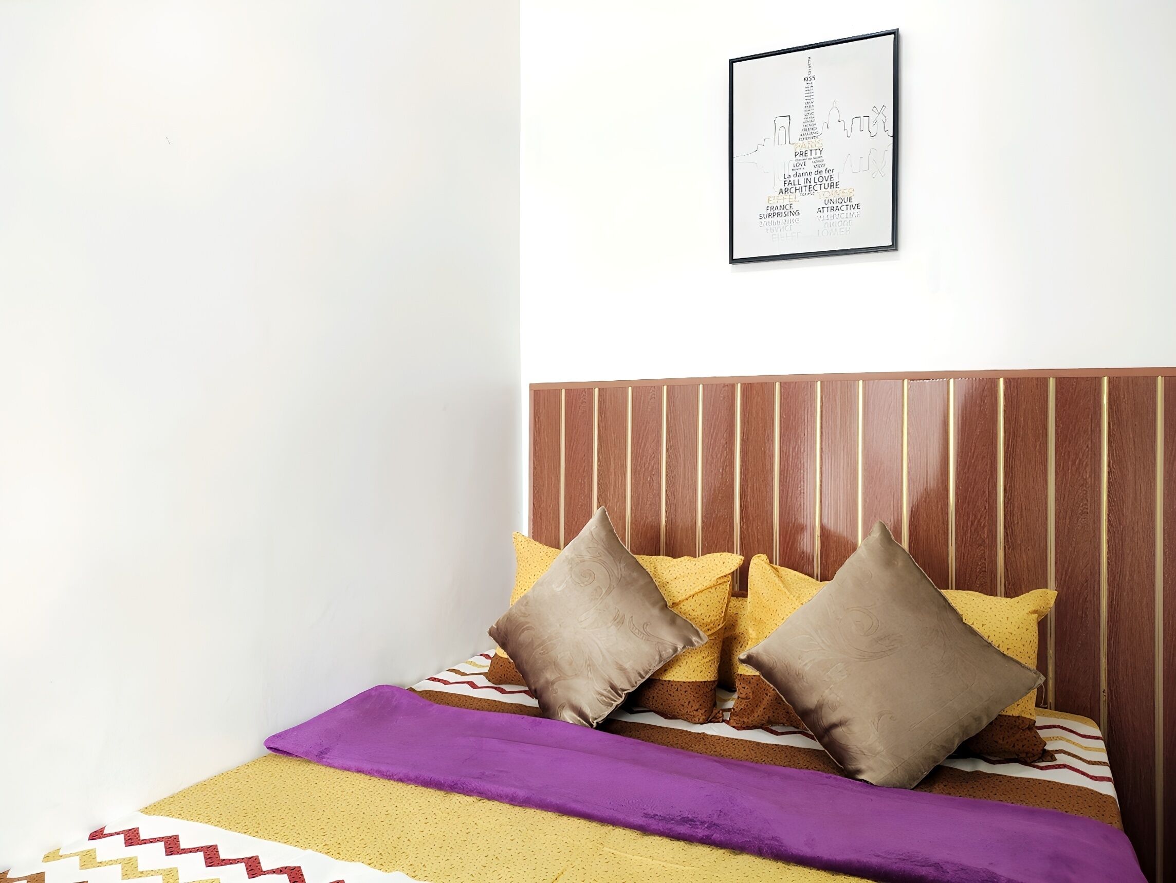 A neatly made bed with a striped bedspread, two pillows, and a purple blanket.