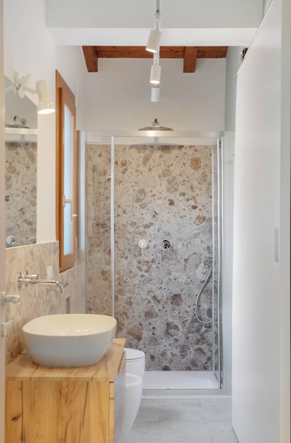 Une salle de bain moderne avec un lavabo sur pied, une douche en verre et un pare-baignoire en marbre.