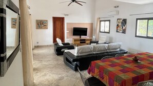 Amplia sala de estar con una mesa de comedor, sofás, televisor y ventilador de techo.