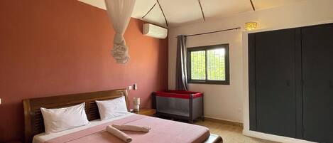 A bedroom with a wooden bed, a bedside table, a window with curtains, and a wardrobe.
