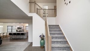A spacious living area with a staircase leading to an upper floor, a kitchen area, and a dining space. - Pocono Mountain Escape! Fire pit•Hot tub•Games•Pool•Lake•Fishing•Golf•Ski•Hiking (Tobyhanna)