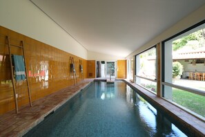 An indoor swimming pool with tiled walls and a view of the outside.