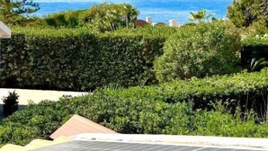A coastal view with a pine tree and dense greenery in the foreground, leading to a clear blue sea. - Villa Sapphires 94 (Plemmirio)
