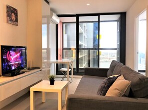 Relax in this stylish living space with a flat-screen TV, comfortable sofa, and a balcony offering city views.