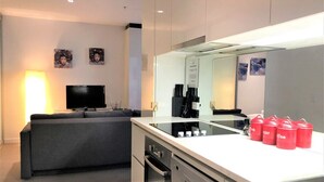 Uma cozinha moderna com ilha central, forno embutido e televisão de tela plana.