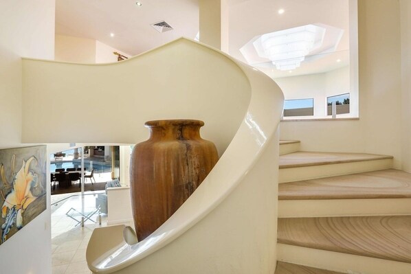 A spiral staircase with a large vase on the landing.
