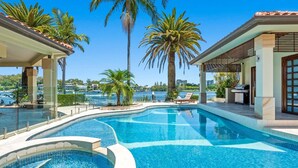 A swimming pool with a hot tub, surrounded by palm trees and a view of the sea. - Main River Grandeur Mansion, 5 Bedroom, Pool & Sauna (Surfers Paradise)