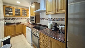 A kitchen with wooden cabinets, a stainless steel refrigerator, a microwave, an oven, a dishwasher, and a coffee maker. - Solmar Javea - Charming apartment in the heart of Javea with garage space (Xàbia)