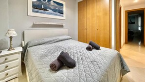 A bedroom with a bed, a nightstand, a lamp, a wardrobe, and a framed picture on the wall. - Solmar Javea - Charming apartment in the heart of Javea with garage space (Xàbia)