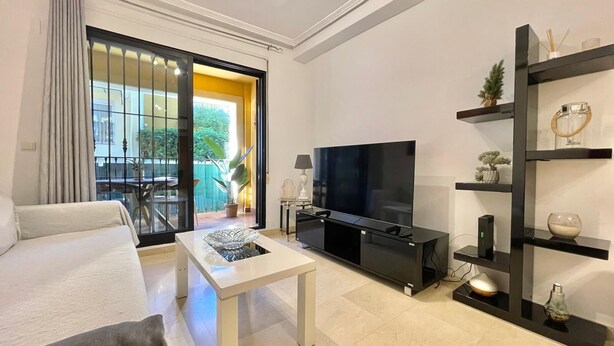 A modern living room with a flat-screen TV, a white sofa, a coffee table, and a black entertainment unit. - Solmar Javea - Charming apartment in the heart of Javea with garage space (Xàbia)