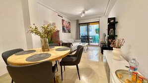 A modern dining area with a wooden table, grey upholstered chairs, and a vase with flowers. - Solmar Javea - Charming apartment in the heart of Javea with garage space (Xàbia)