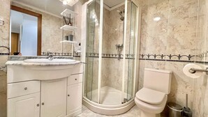 A bathroom with a curved shower enclosure, a toilet, and a vanity with a sink. - Solmar Javea - Charming apartment in the heart of Javea with garage space (Xàbia)