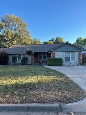 A two-story house with a garage, a stone facade, and a well-maintained lawn. - Walking distance to the Stadium! Charming 3-bedroom house in lovely Norman (Norman)